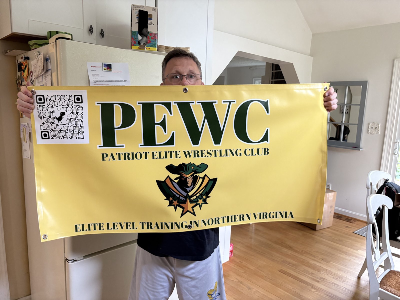 A man holding the banner Big Event Signs produced for Potomac Elite Wrestling Club